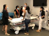 A group of residents and attendings bending over a patient in a hospital bed.